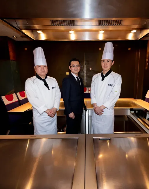 The executive chef, the director and a senior cook of a Japanese teppanyaki restaurant, side by side at the counter